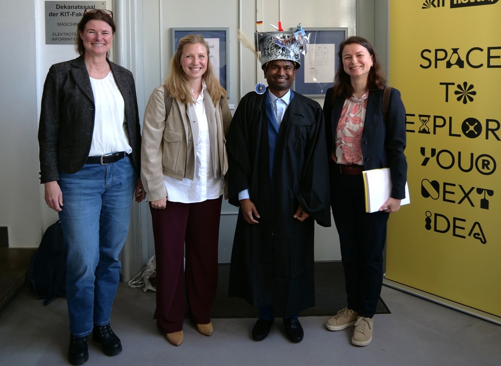 Four people posing for a photo, with one person wearing a graduation gown and a decorated hat.